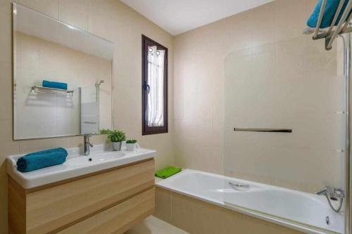 uma casa de banho com um lavatório, uma banheira e um espelho. em Villa Aguamarina em Playa Blanca