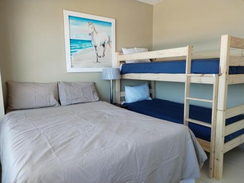 a bedroom with a bed and two bunk beds at High Tide in Amanzimtoti
