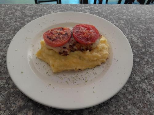a white plate with a piece of food with tomatoes on it at Hotel Isabella Tayrona in Los Naranjos