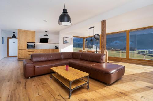 a living room with a brown leather couch and a table at Exklusives Chalet-Haus mit Gletscherblick in Neukirchen am Großvenediger