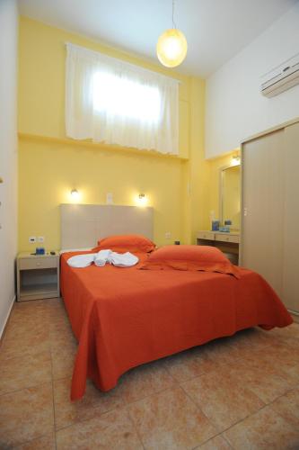a bedroom with a large orange bed with two towels at Aigaio Studios tinos in Tinos Town