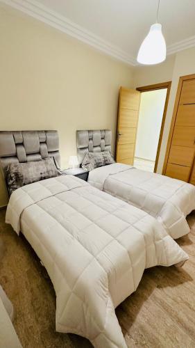 two large beds in a bedroom with a large white bed at Apartement sur la corniche, vue sur mer in Rabat