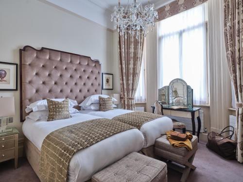 a large bedroom with a large bed and a chandelier at The Apartments by The Sloane Club in London