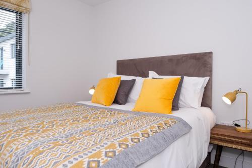 a bedroom with a large bed with yellow pillows at 4 Rockham - Luxury Apartment at Byron Woolacombe, only 4 minute walk to Woolacombe Beach! in Woolacombe