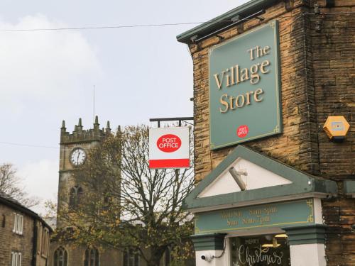 a sign for the village store on a building with a clock tower at Howard's Hideaway in Hayfield