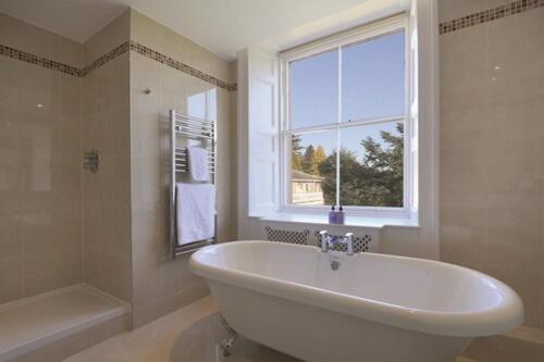 a bathroom with a large white tub and a window at Macdonald Leeming House in Watermillock