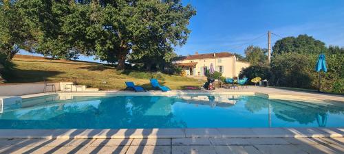 - une grande piscine avec des chaises bleues dans la cour dans l'établissement Maison Lamothe, à Flamarens