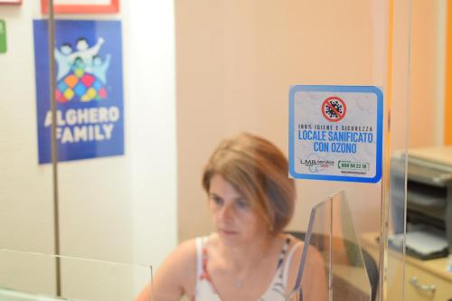 une femme debout devant un miroir avec un panneau dans l'établissement Actinia Accommodation, à Alghero