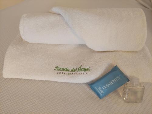 a towel with a bottle of soap next to two towels at Posada del Ángel in Pachuca de Soto