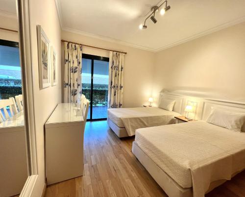 um quarto de hotel com duas camas e uma varanda em Olivos del golf - Terrace with pool by HD em Vilamoura