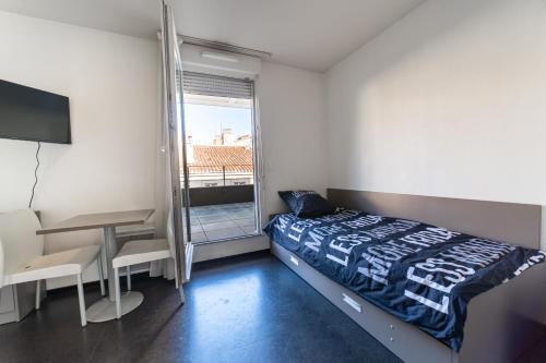 um quarto com uma cama, uma secretária e uma janela em Le Stratège em Marselha