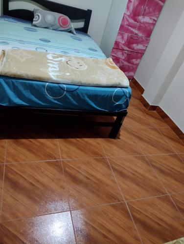 1 dormitorio con 1 cama y suelo de madera en HOSPEDAJE NELLY, en Puerto Chicama