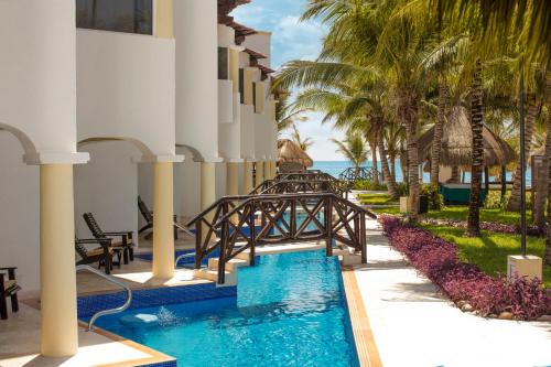 a resort with a bridge over a pool and palm trees at Hidden Beach Resort Au Naturel Adults Only Catamarán, Cenote & More Inclusive in Akumal