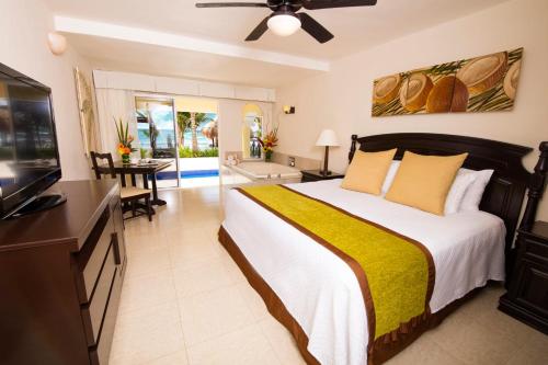 a bedroom with a large bed and a living room at Hidden Beach Resort Au Naturel Adults Only - All Inclusive in Akumal