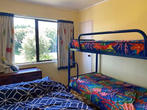 a bedroom with two bunk beds and a window at Amongst the Action - Te Kaha in Te Kaha