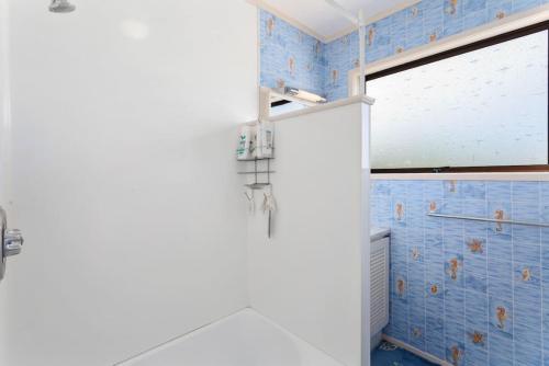 a bathroom with blue tiled walls and a shower at Amongst the Action - Te Kaha in Te Kaha