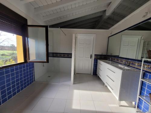 ein Bad mit blauen und weißen Fliesen und einem Fenster in der Unterkunft El Chaparral in Candeleda