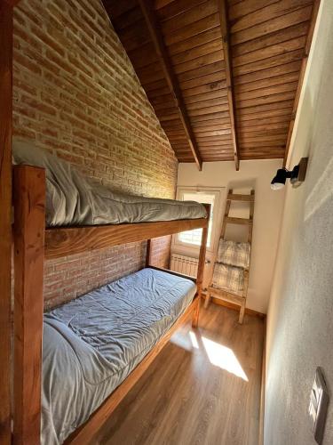 a bedroom with a bunk bed and a brick wall at La Pampita en Villa Arelaquen Casa M14 in San Carlos de Bariloche