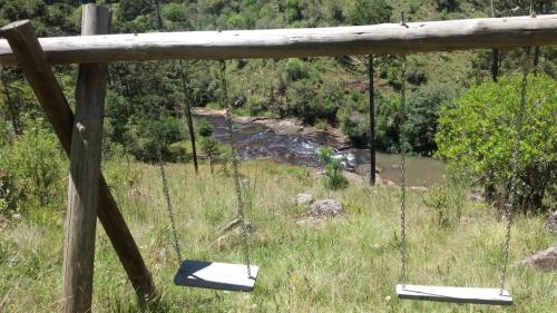 twee schommels hangend aan een houten hek bij een rivier bij Casa de Campo da Vó in Urupema