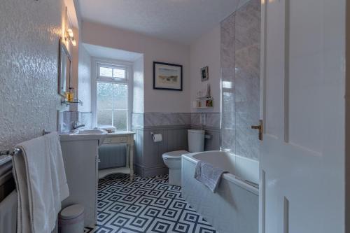 een badkamer met een bad, een toilet en een wastafel bij Glyntwrog House in Betws-y-coed