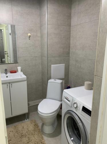 a bathroom with a toilet and a washing machine at # 50 Солнечная комфортная студия in Atyrau