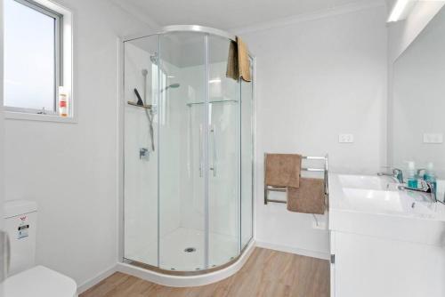 a white bathroom with a shower and a sink at Waiotahe Executive Getaway in Opotiki