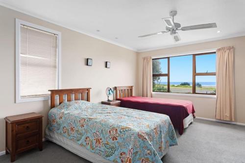a bedroom with two beds and a large window at Wonderful Waiotahe Beach in Waiotahi