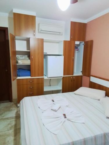 1 dormitorio con 1 cama blanca grande y armarios de madera en Clube Praiano, en Cabo Frío