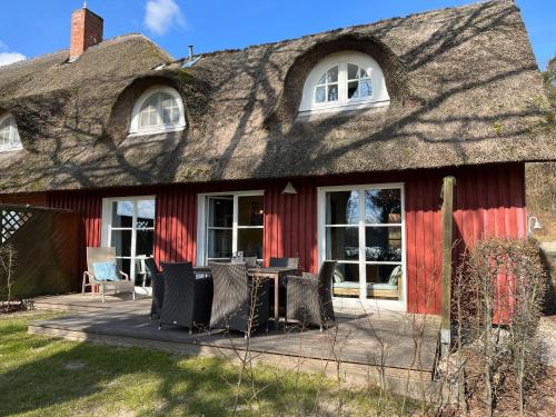 a thatch roofed house with a table and chairs at Ferien direkt am Wasser mit Hund in Krakow am See