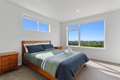 a bedroom with a bed and a large window at Okioki Te Kaha Holiday Home in Te Kaha