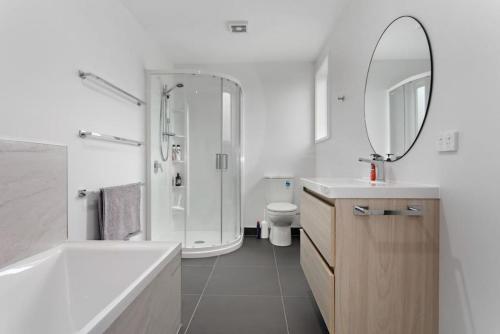 uma casa de banho com uma banheira, um lavatório e um espelho. em Okioki Te Kaha Holiday Home em Te Kaha