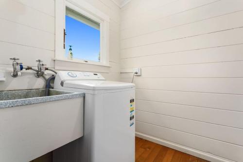 a white laundry room with a washer and dryer at Andam Cottage, Central Opotiki in Opotiki