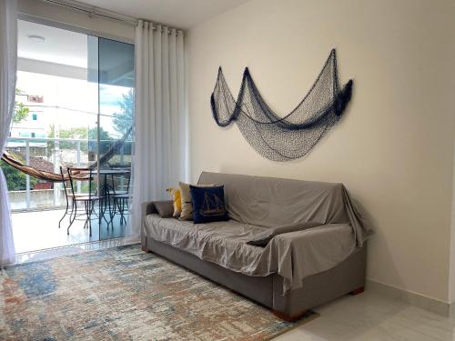 un sofá en una sala de estar con una red en la pared en Apto de alto padrão 100 m da Praia de Costazul - WIFI 200MB - TV Smart - 2 Quartos - Garagem - Cozinha equipada - Churrasqueira, en Rio das Ostras