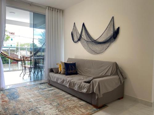 a couch in a living room with a net on the wall at Apto de alto padrão 100 m da Praia de Costazul - WIFI 200MB - TV Smart - 2 Quartos - Garagem - Cozinha equipada - Churrasqueira in Rio das Ostras