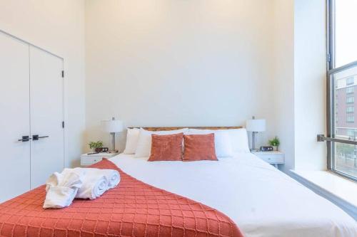 - une chambre avec un grand lit blanc et des oreillers orange dans l'établissement Downtown Beauty mins to Airport+FREE Parking+Games, à Newark