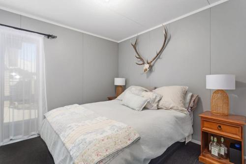 a white bedroom with a bed and a window at Lifes a Beach at Waiotahe Beach Estate in Waiotahi