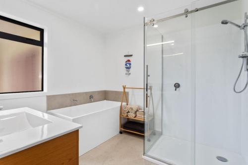 a bathroom with a shower and a tub and a sink at Kate and Harrys in Opotiki