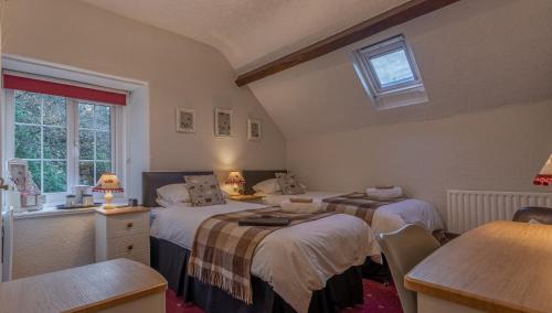 a bedroom with two beds and a table and a window at Glyntwrog House in Betws-y-coed