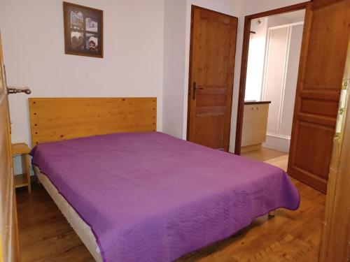 ein Schlafzimmer mit einem Bett mit einer lila Decke in der Unterkunft Appartement Brides-les-Bains, 3 pièces, 6 personnes - FR-1-512-264 in Brides-les-Bains