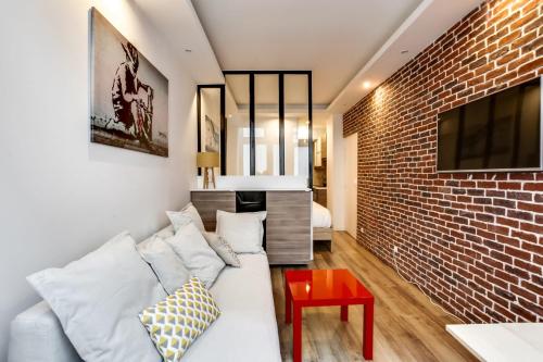 salon z białą kanapą i ceglaną ścianą w obiekcie Modern apartment - 1BR-4P - Palais Garnier w Paryżu