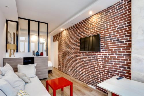 d'un salon avec un canapé et une télévision. dans l'établissement Modern apartment - 1BR-4P - Palais Garnier, à Paris