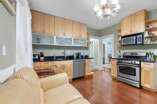 a kitchen with wooden cabinets and a couch in a room at Bright & Spacious 3BR, Mins from Downtown, Easy to Gillette, Parking in Boston