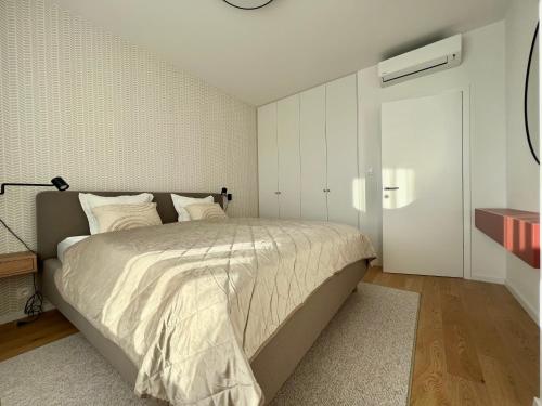 een slaapkamer met een groot bed met witte muren bij Klingerka brand new 1-bedroom apartment free parking in Nivy