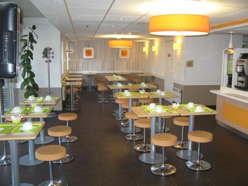 a restaurant with rows of tables and stools at ibis Budget Gennevilliers Asnieres in Gennevilliers