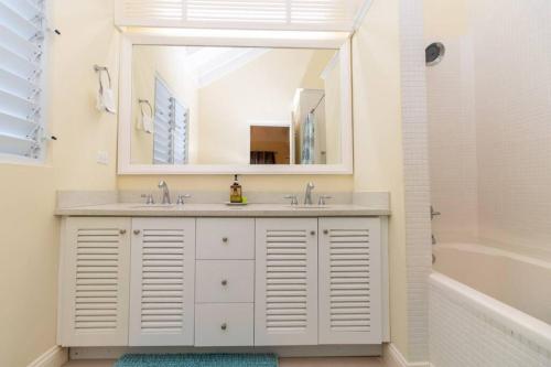 a bathroom with a sink and a mirror and a tub at Richmond Estate With Pool House in Ocho Rios