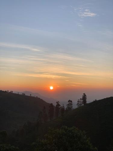 a sunset on a hill with the sun setting on the horizon at DIAMOND HILL VIEW in Ketti