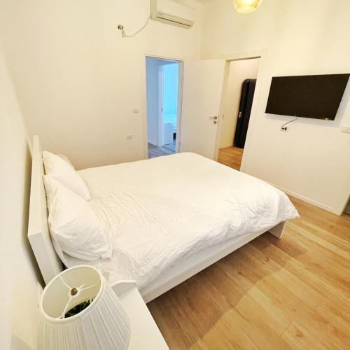 a white bedroom with a bed and a television at Luz Mansion ~ Lux & Comfy in Rishon LeẔiyyon