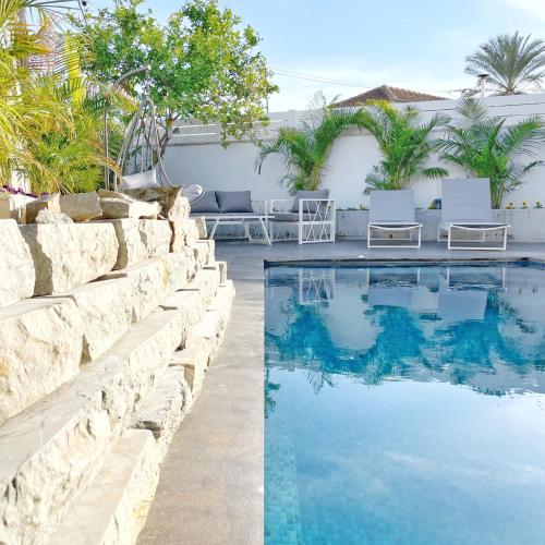 una piscina con 2 sillas junto a una pared en Luz Mansion ~ Lux & Comfy en Rishon LeẔiyyon