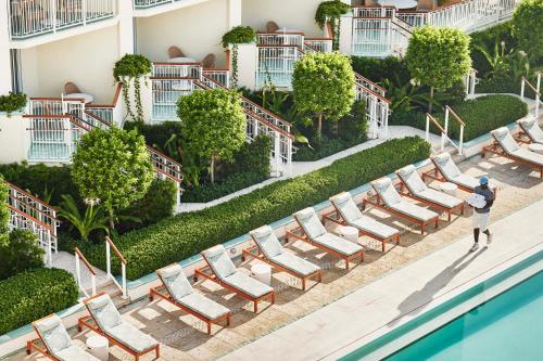 a row of lounge chairs next to a pool at a hotel at Four Seasons Resort Palm Beach in Palm Beach