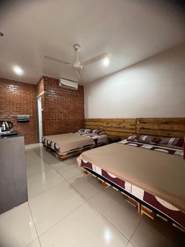 een kamer met 2 bedden en een bakstenen muur bij Ujud Sepakat Homestay in Melaka